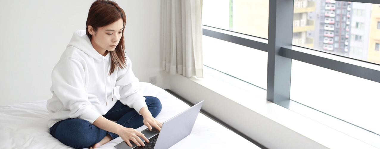 Female sat on bed with laptop
