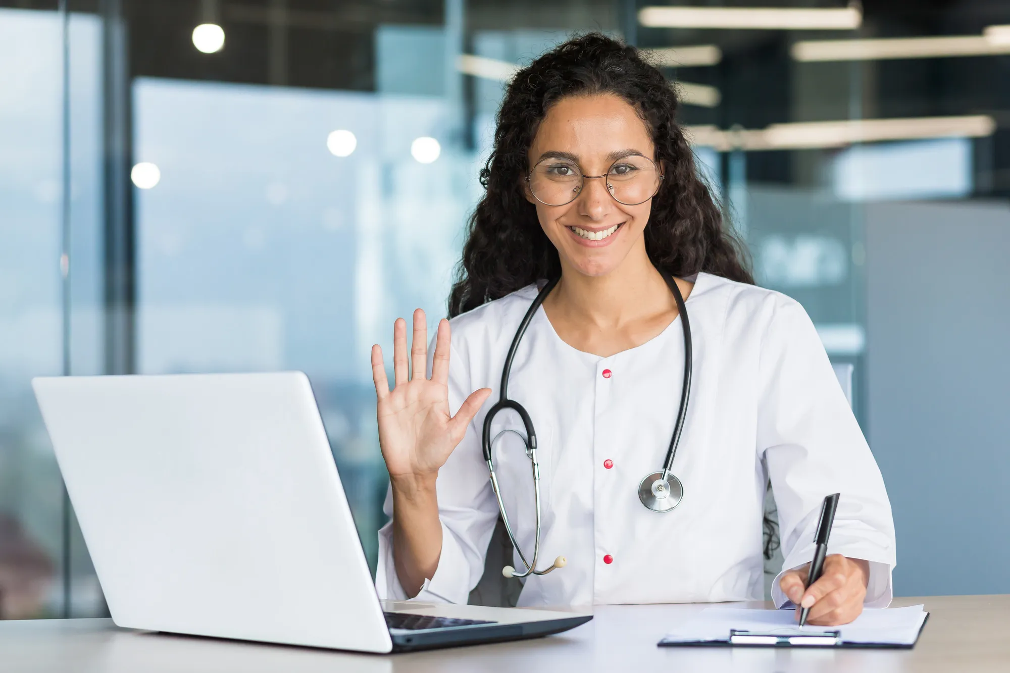 Female doctor waving at laptop